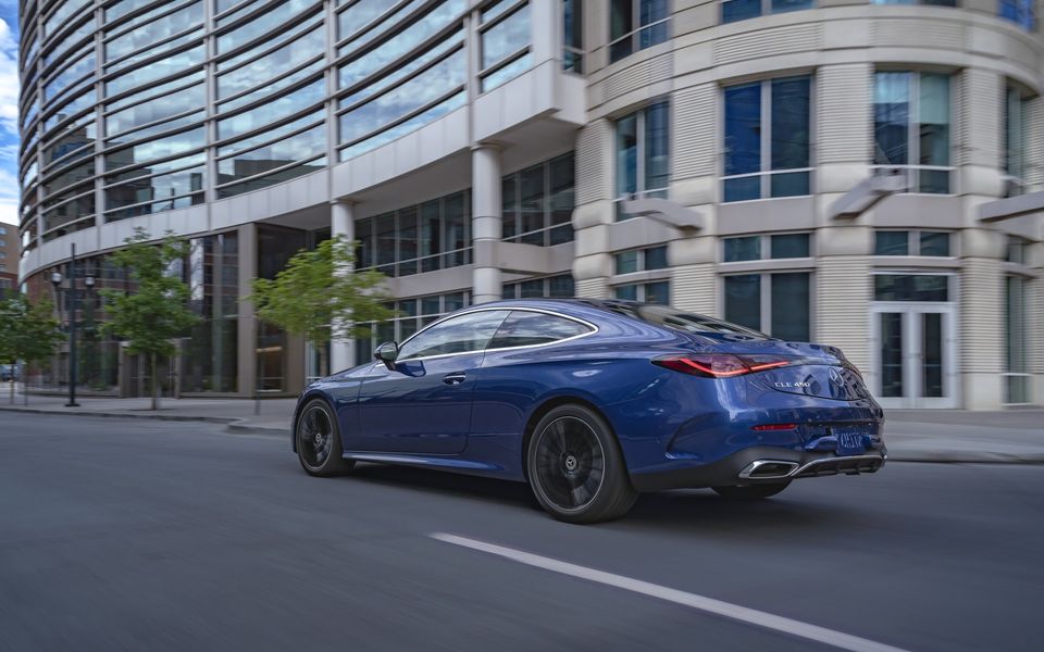 Blue Mercedes-Benz CLE 450 coupe driving past an office building